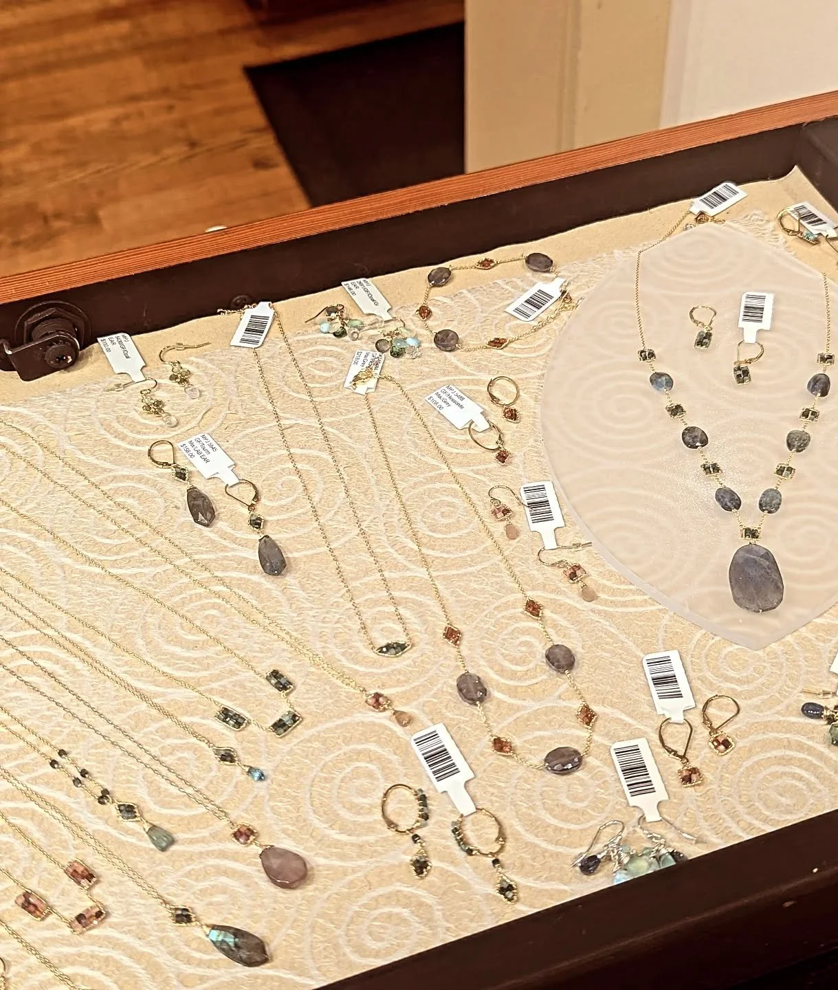Display of various necklaces and earrings with purple and gold stones in a jewelry box.
