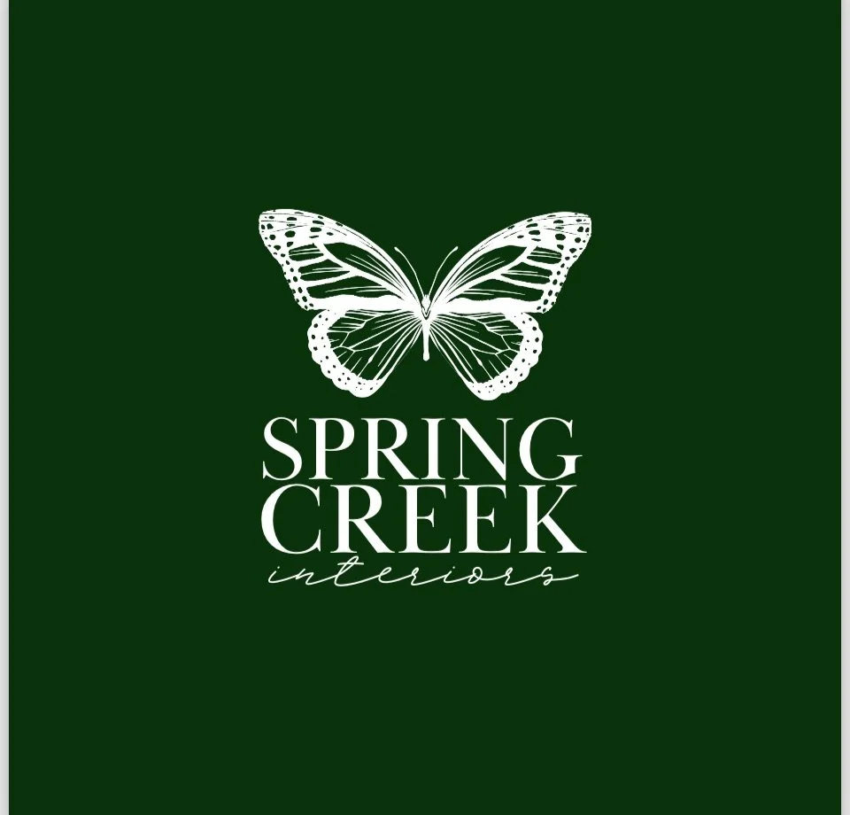Green background with a white butterfly illustration above the text 'Spring Creek Interiors' in white, elegant cursive and block fonts.