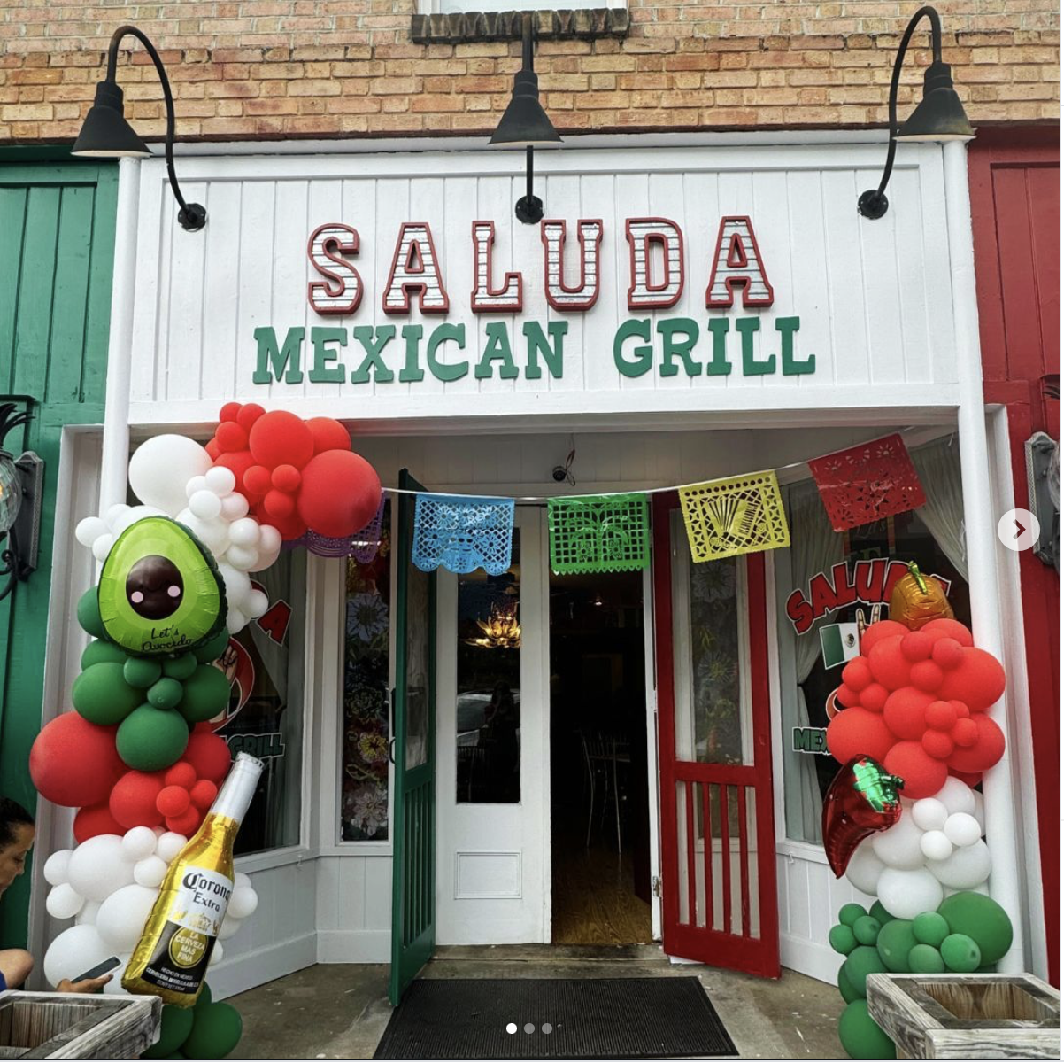 Front entrance of Saluda Mexican Grill adorned with colorful balloons, paper banners, and decorations celebrating Cinco de Mayo.