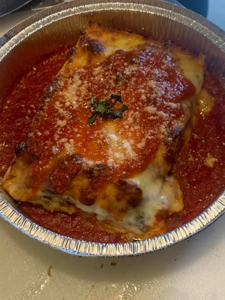 Lasagna with tomato sauce and melted cheese in a foil container