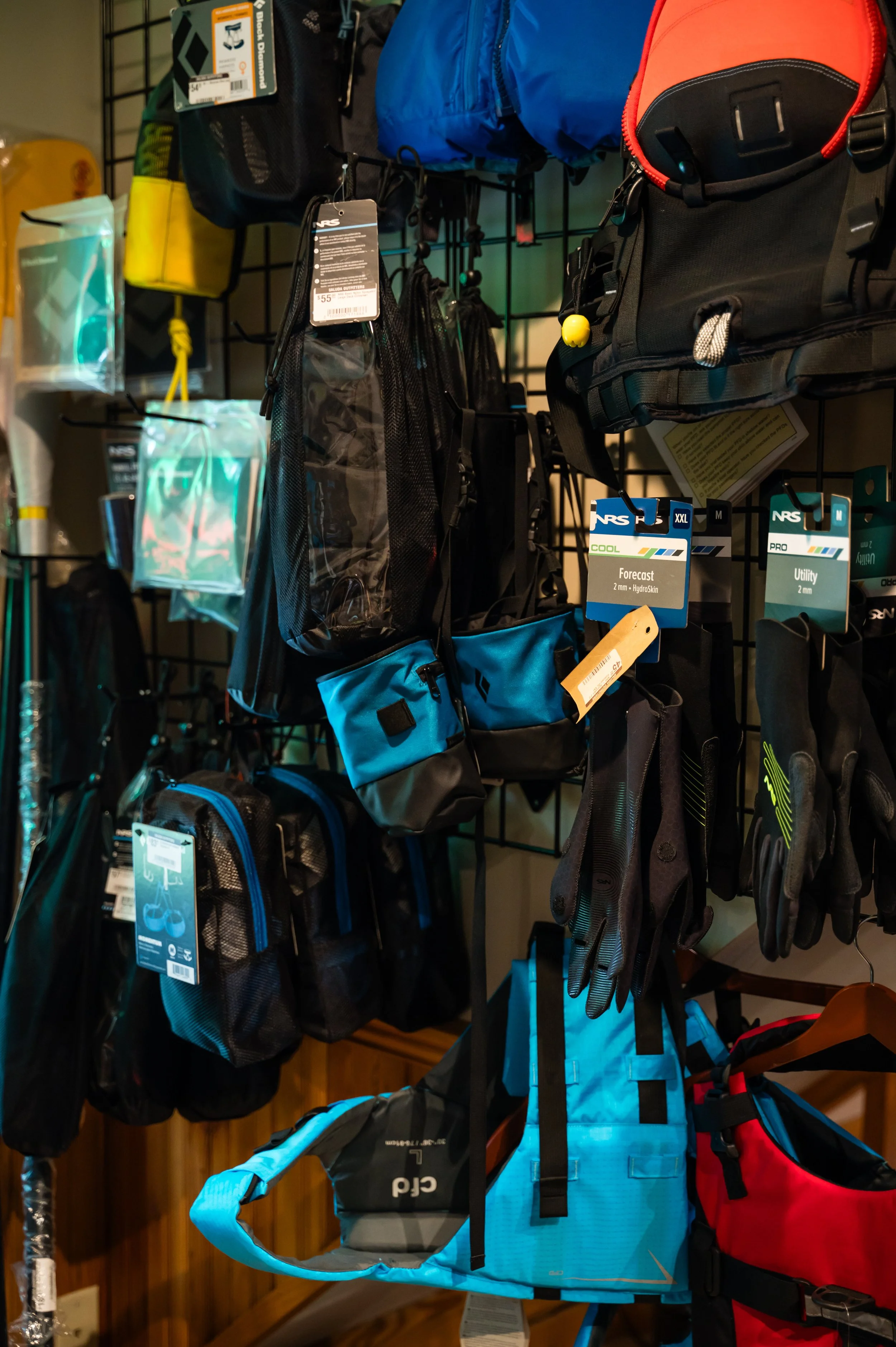Display of backpacks, hydration packs, and outdoor gear on a metal grid wall at a sporting goods store.