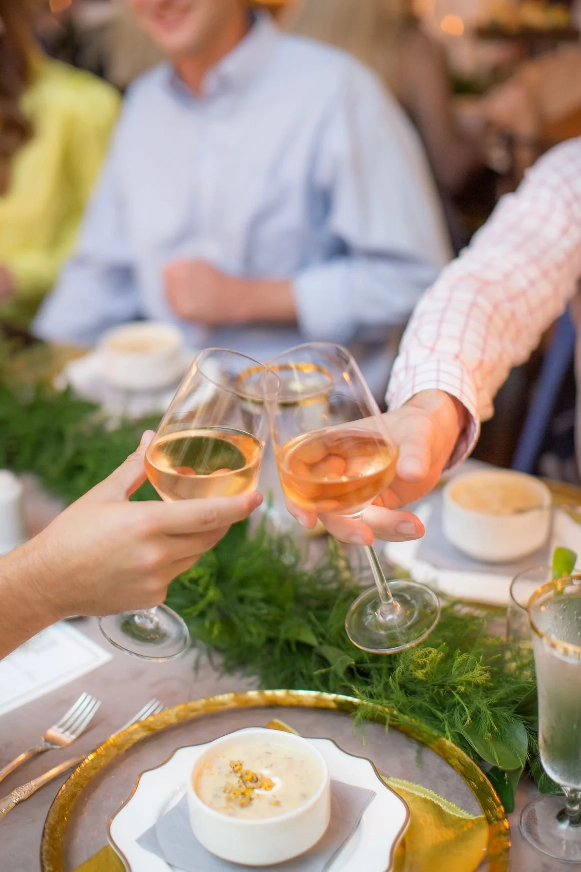 People clinking glasses of rosé wine at a meal celebration.