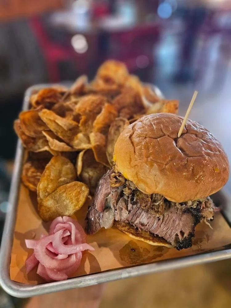Barbecue beef sandwich with potato chips and pickled onions.