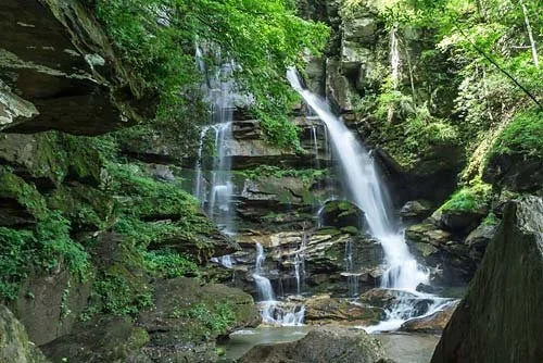 Waterfall cascading over rocks in a lush green forest.
