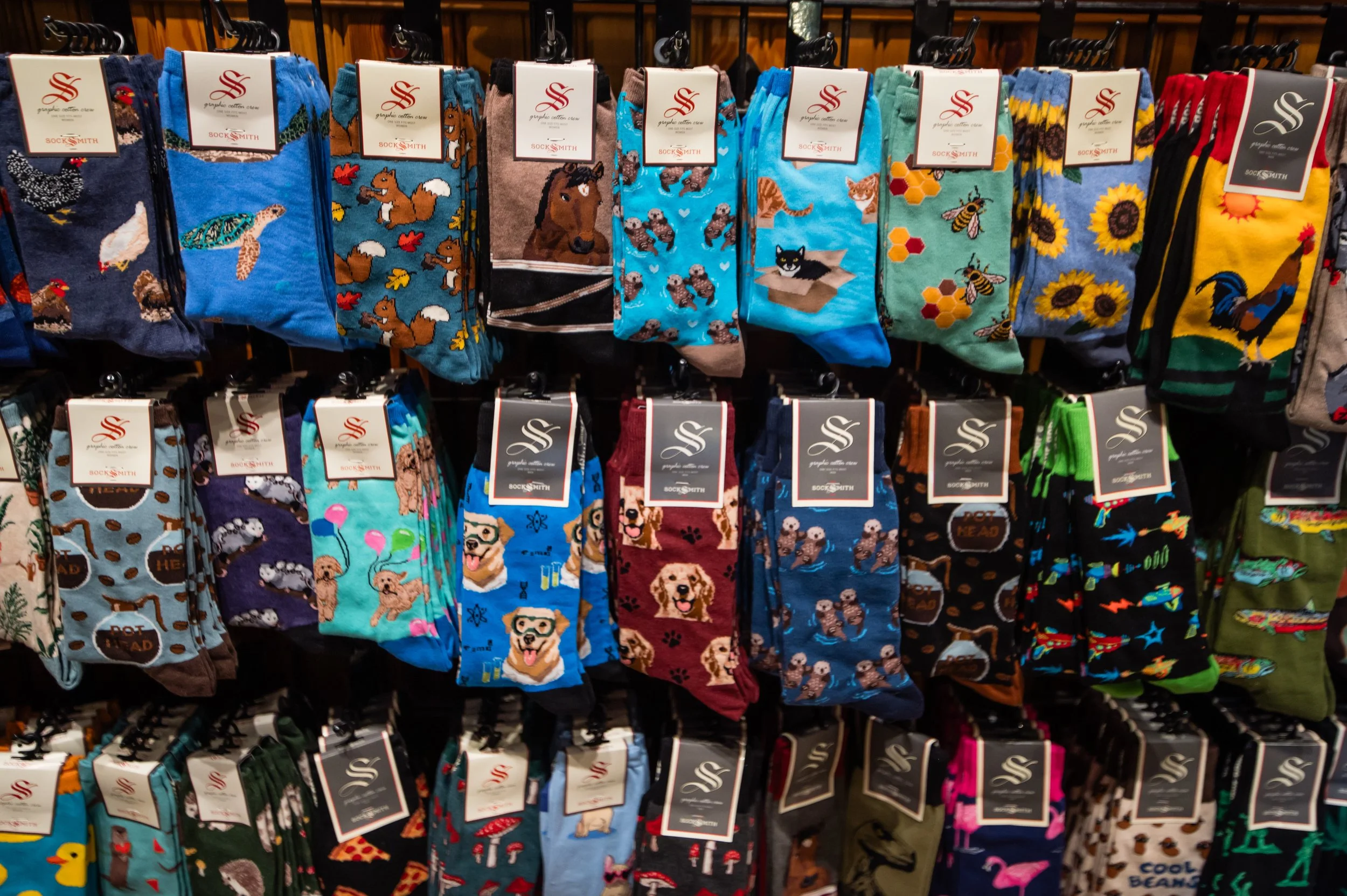 Display of colorful socks with various animal prints and patterns hanging on a rack in a store.