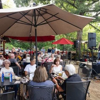 People dining outdoors at tables under large umbrellas at a social gathering.