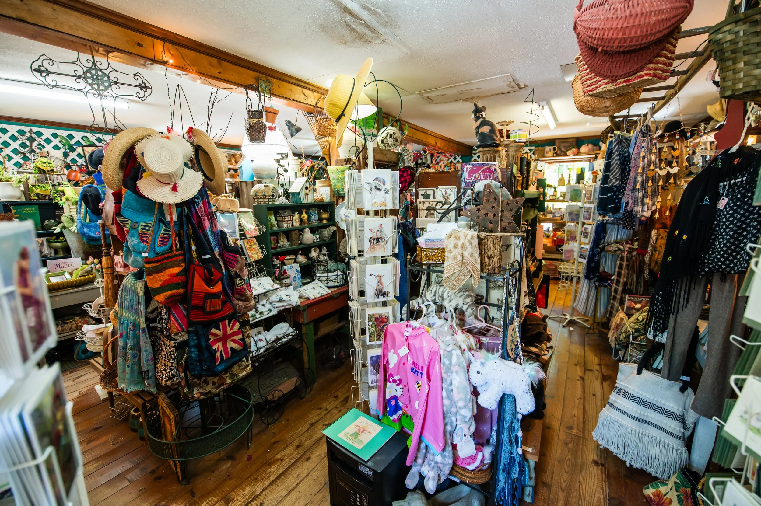 Interior of a thrift store with clothing, hats, and various decorative items displayed on shelves and racks.