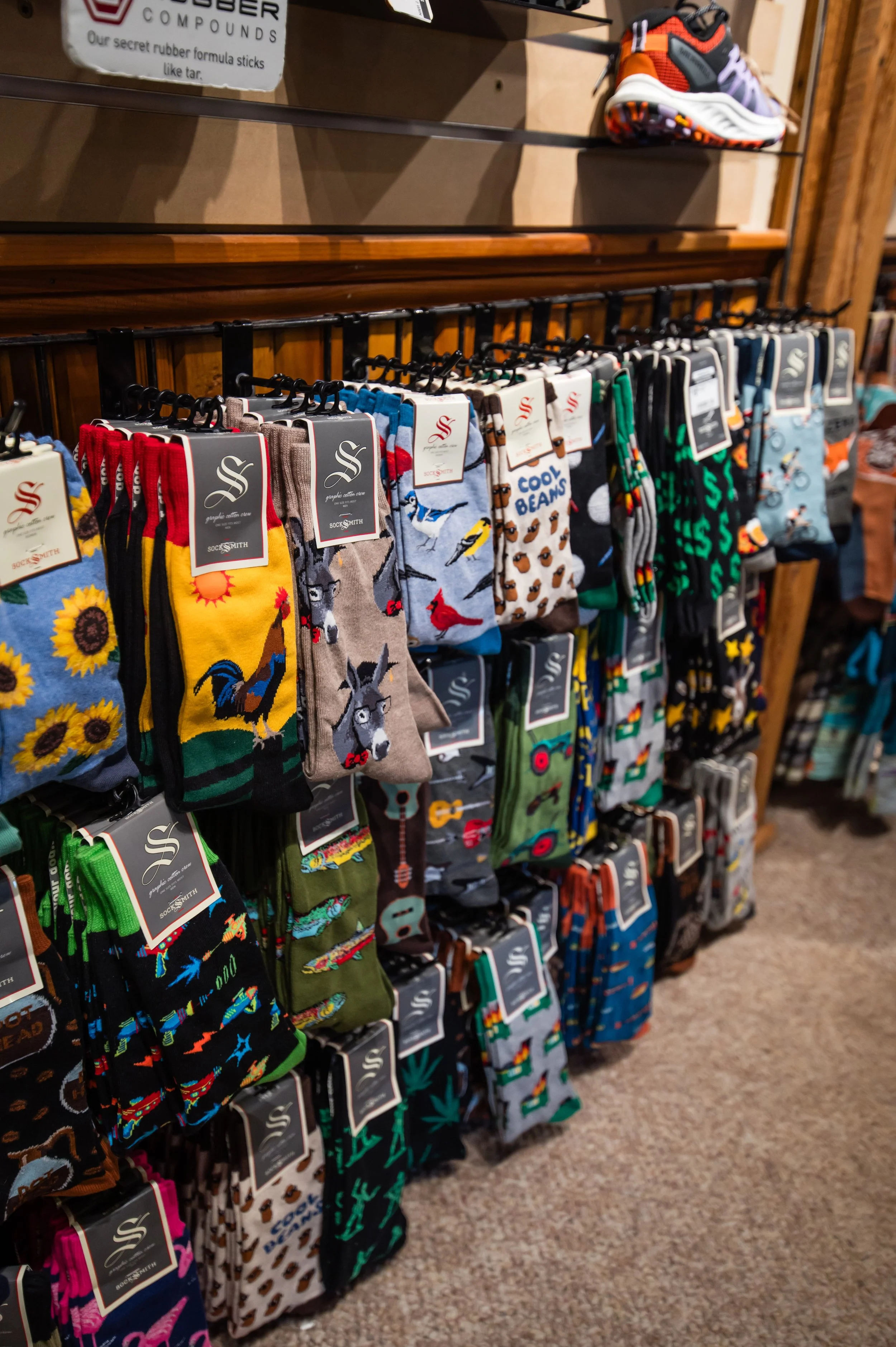 Display of colorful socks with various patterns such as animals, flowers, and abstract designs hanging on a rack in a store.