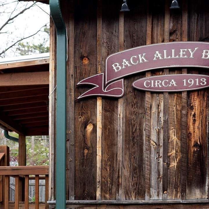 A wooden wall with a sign that reads "Back Alley Bar Circa 1913."