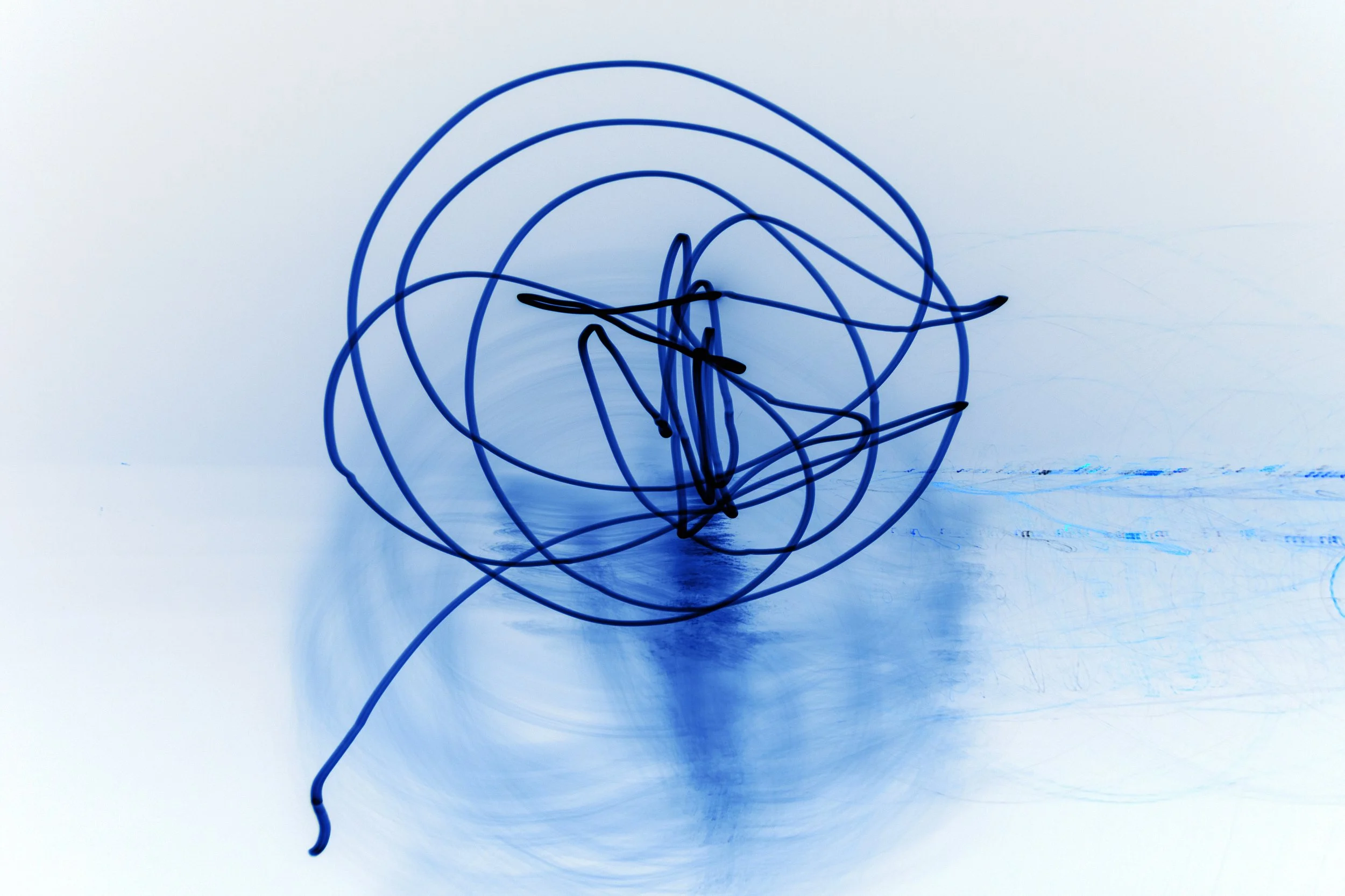 Blue and black wire sculpture against a white background with shadow reflections.