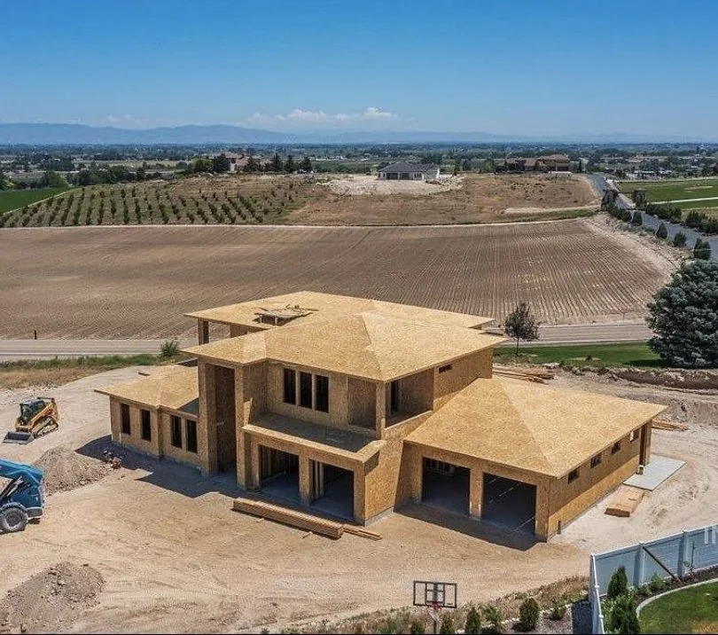 Under-construction house in a rural area surrounded by farmland and open fields.