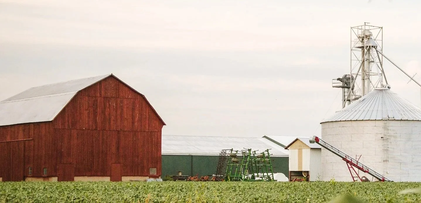 A farm scene with a red barn, green equipment, and a white grain silo.