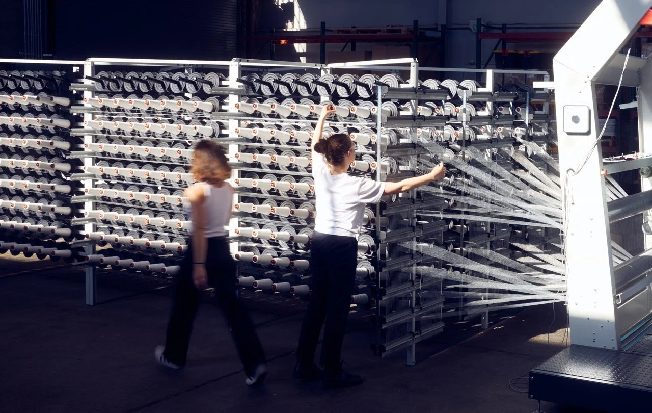 Two women working with fabric weaving machine in a factory