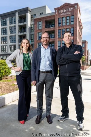 Three business professionals standing outdoors in front of modern office buildings, smiling at the camera.