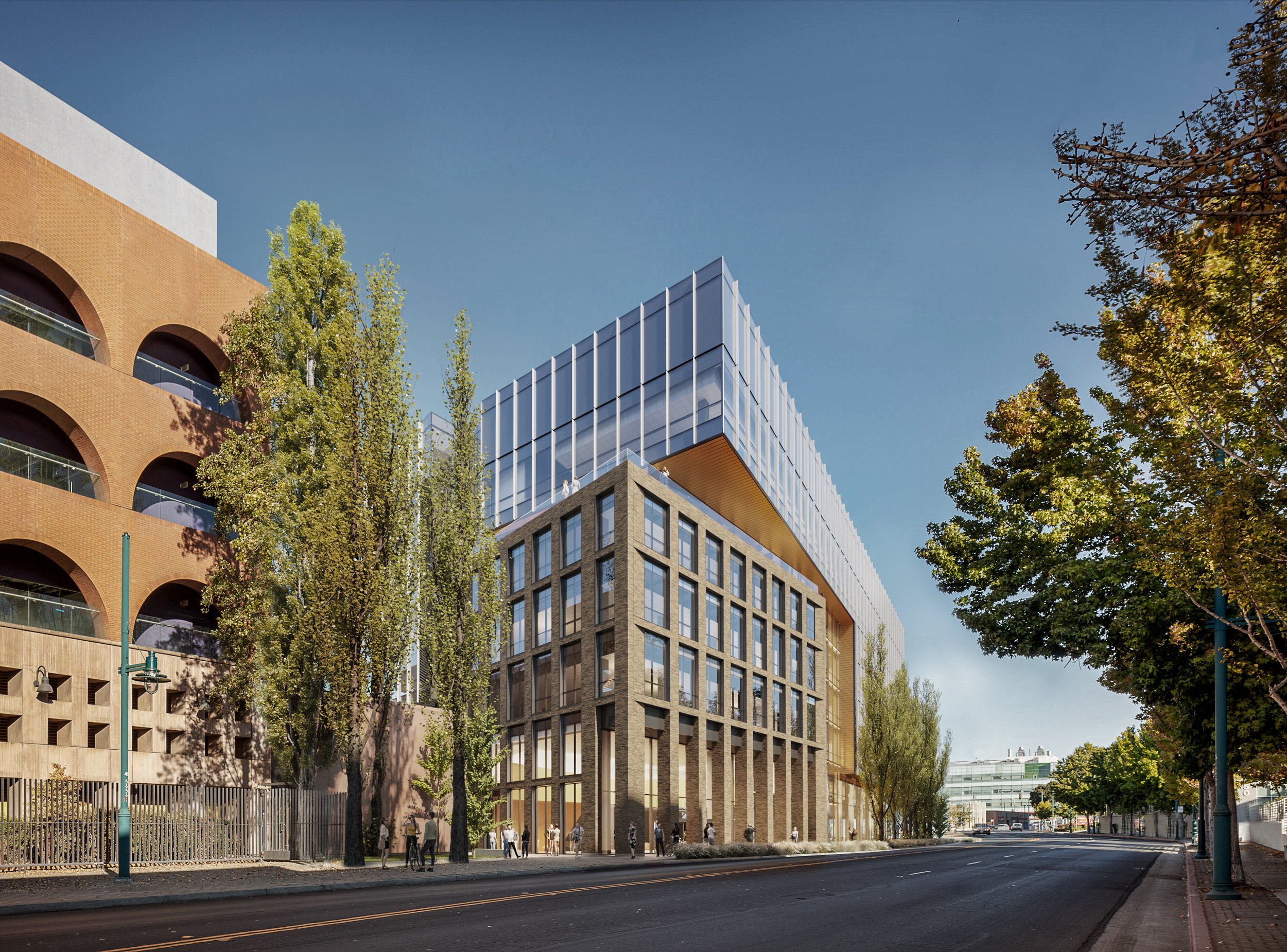 Modern mixed-use building with glass and brick exterior, surrounded by trees on a city street with pedestrians.