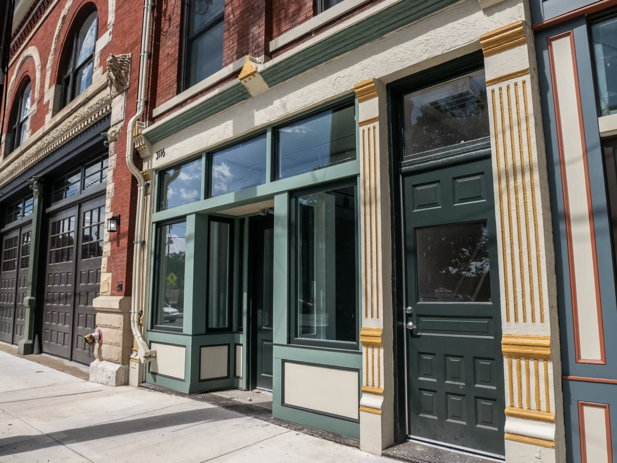 Colorful storefront with large windows and a green door on a city sidewalk