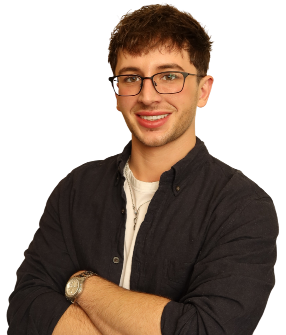 A young man with short brown hair, glasses, wearing a black shirt and white T-shirt, smiling with arms crossed.