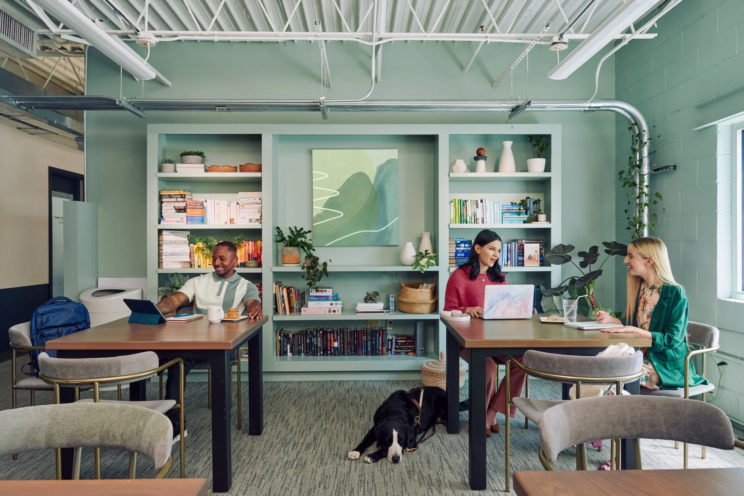 Colleagues with disabilities chat and work together across the table of a bright coworking space.