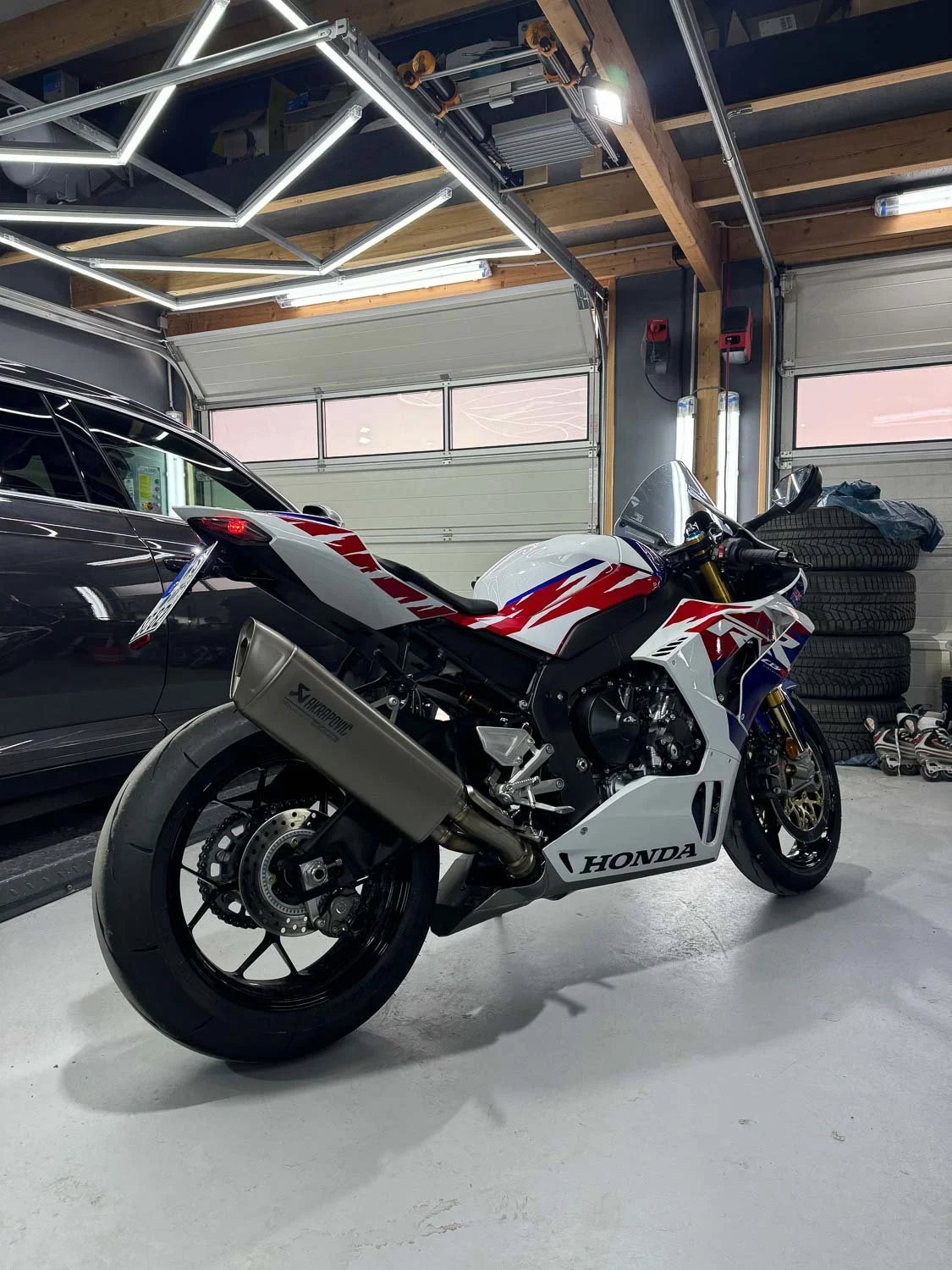 Honda S1000RR Motorrad in einem Reifenlager oder Garage mit Reifenstapeln im Hintergrund.