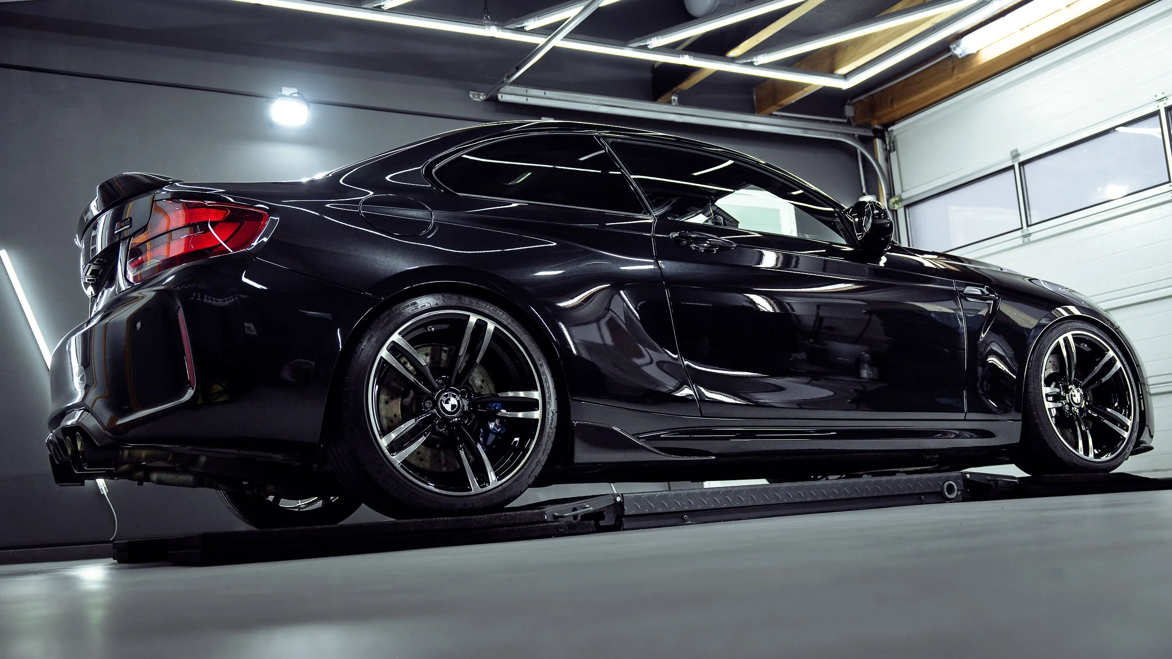 Schwarzer BMW M4 in einer Garage, seitlich fotografiert.