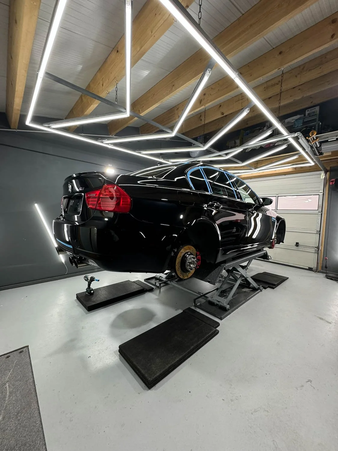 Ein Auto in einer Werkstatt, das gerade repariert wird, mit fehlenden Rädern und spezieller Beleuchtung an der Decke.