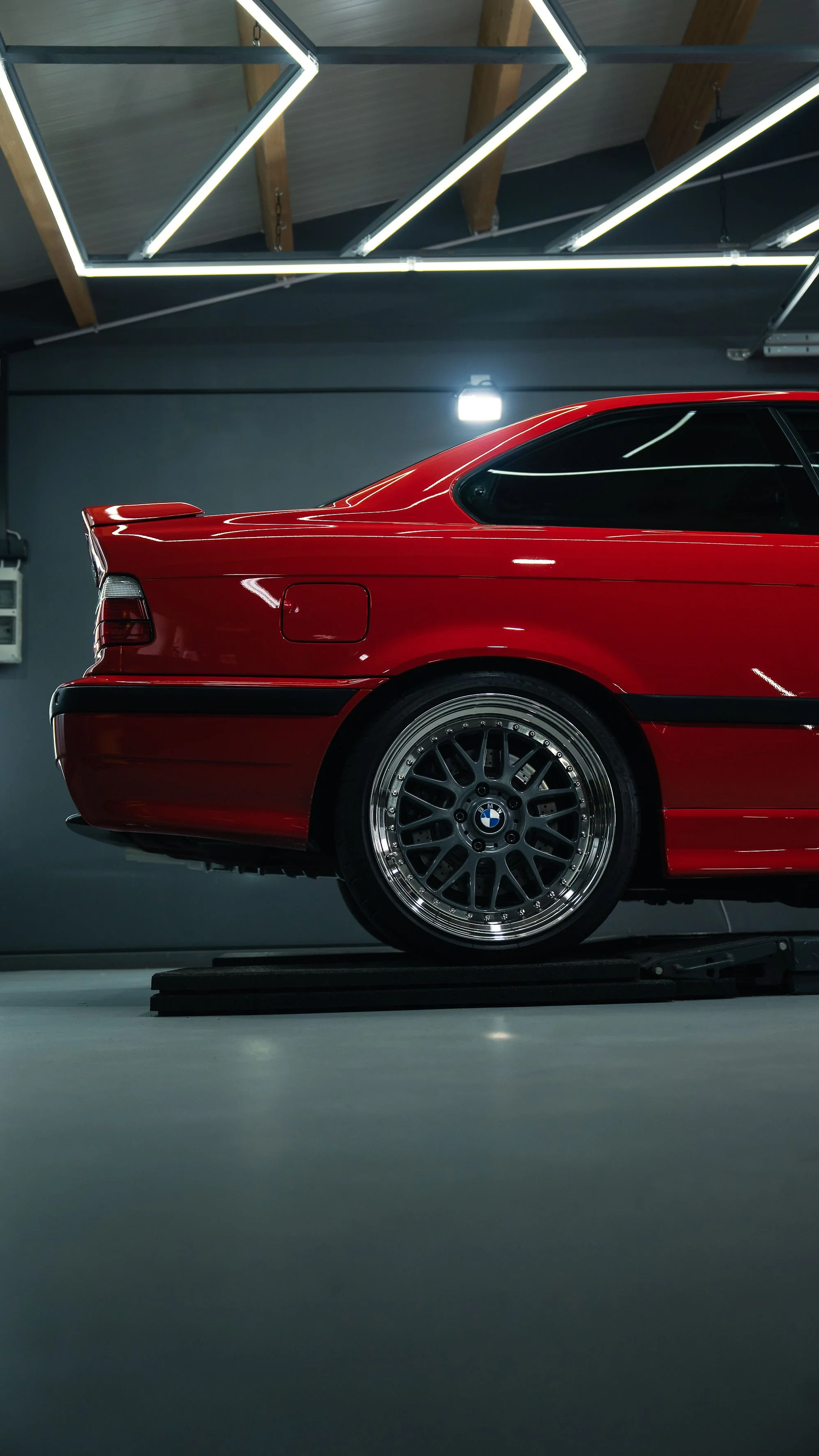 Roter BMW Sportwagen in einer Garage mit moderner Beleuchtung.