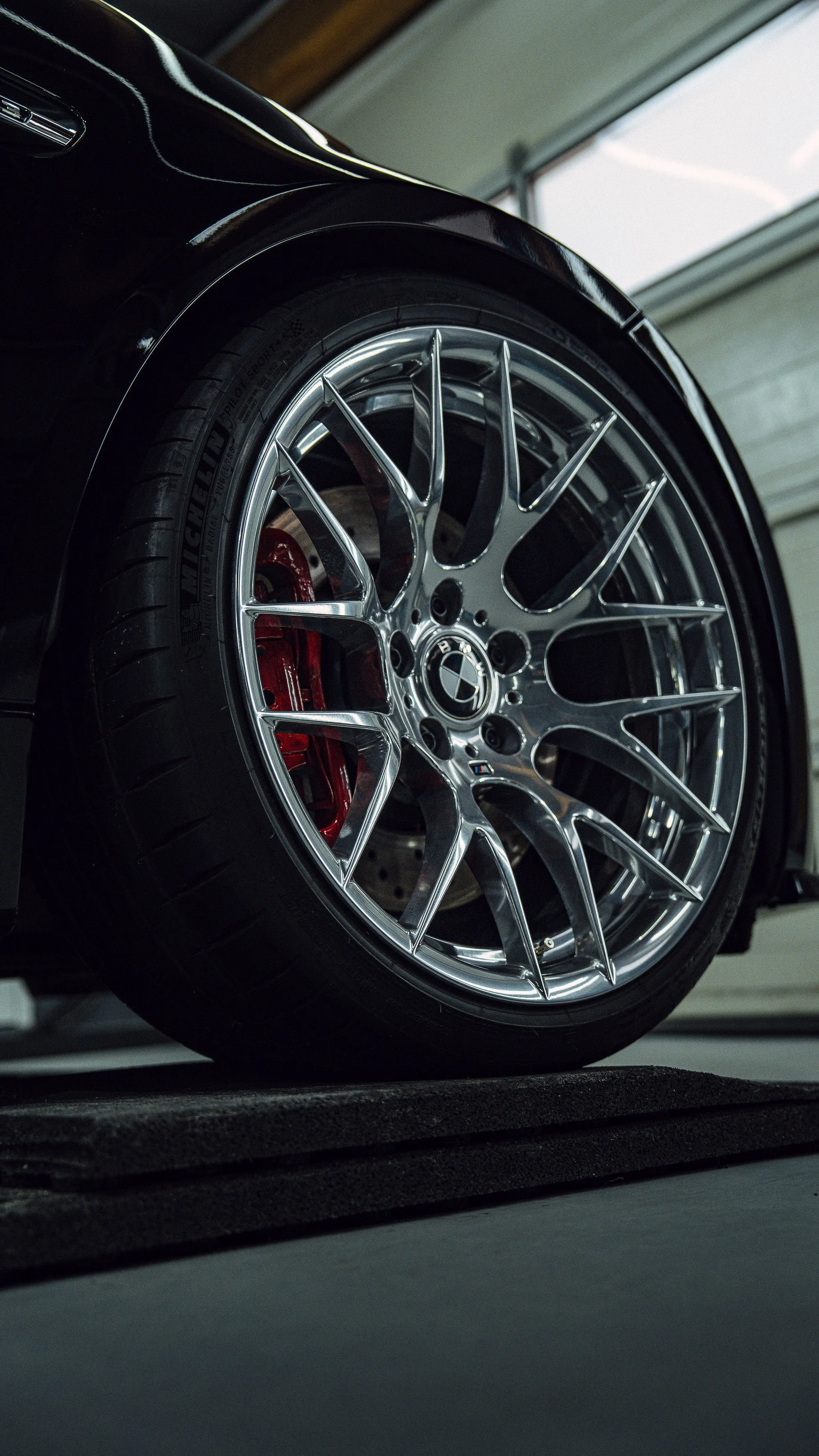 Nahaufnahme eines schwarzen Autos mit chromrad und Michelin-Reifen im Garage