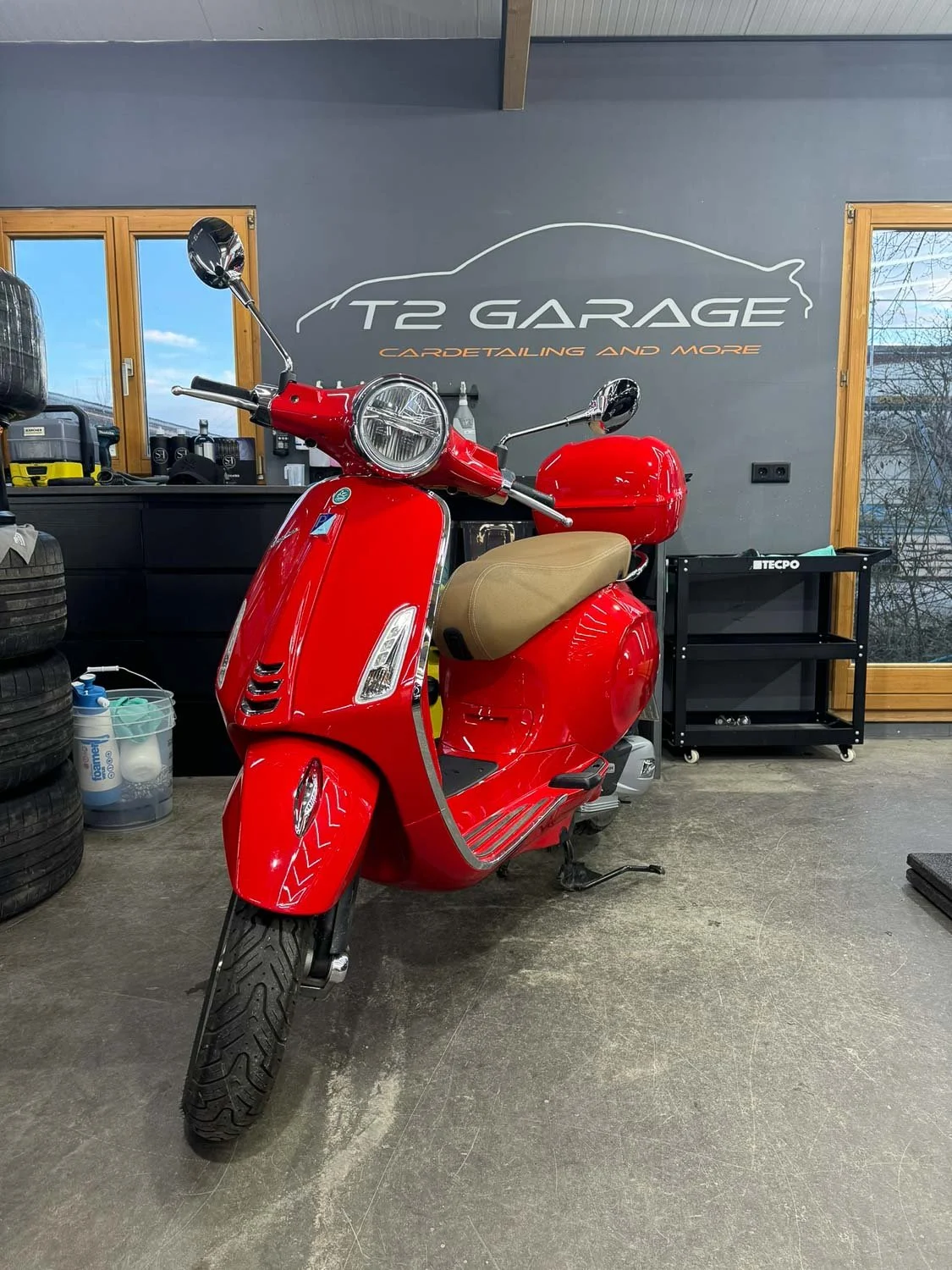 Roter Roller in einer Garage mit Schriftzug 'T2 Garage' an der Wand im Hintergrund.
