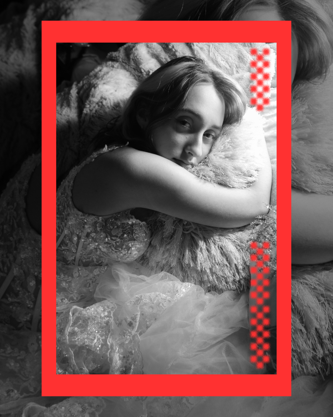 A black and white photo of a woman lying on her side, resting her head on a fluffy pillow. She is wearing a lace dress and looking at the camera with a calm expression. The photo is framed with a red border and decorated with red checkered patterns o