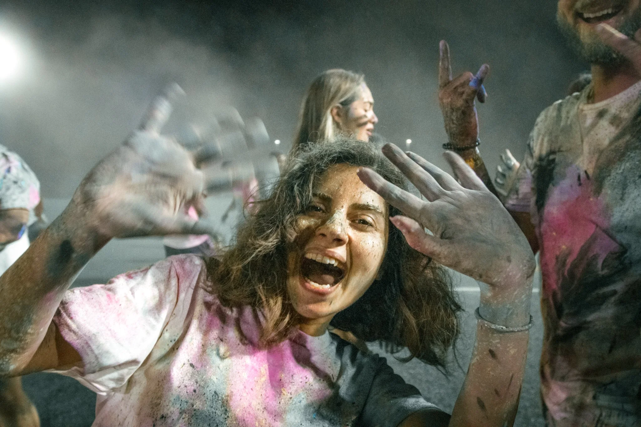 People covered in colorful powder celebrating at a festival, smiling and having fun.