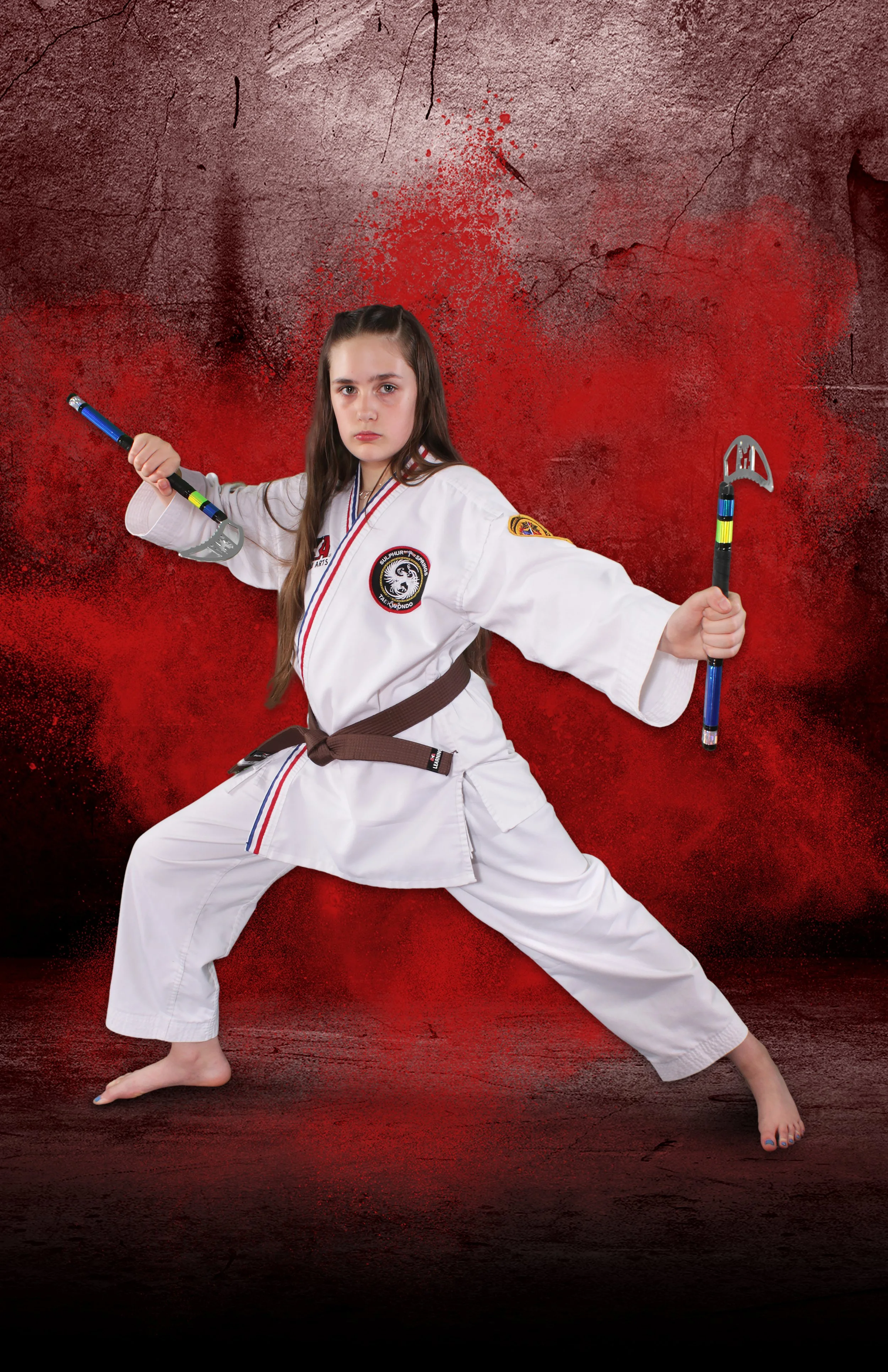 An image of a preteen girl holding martial arts weapons with a serious expression on her face