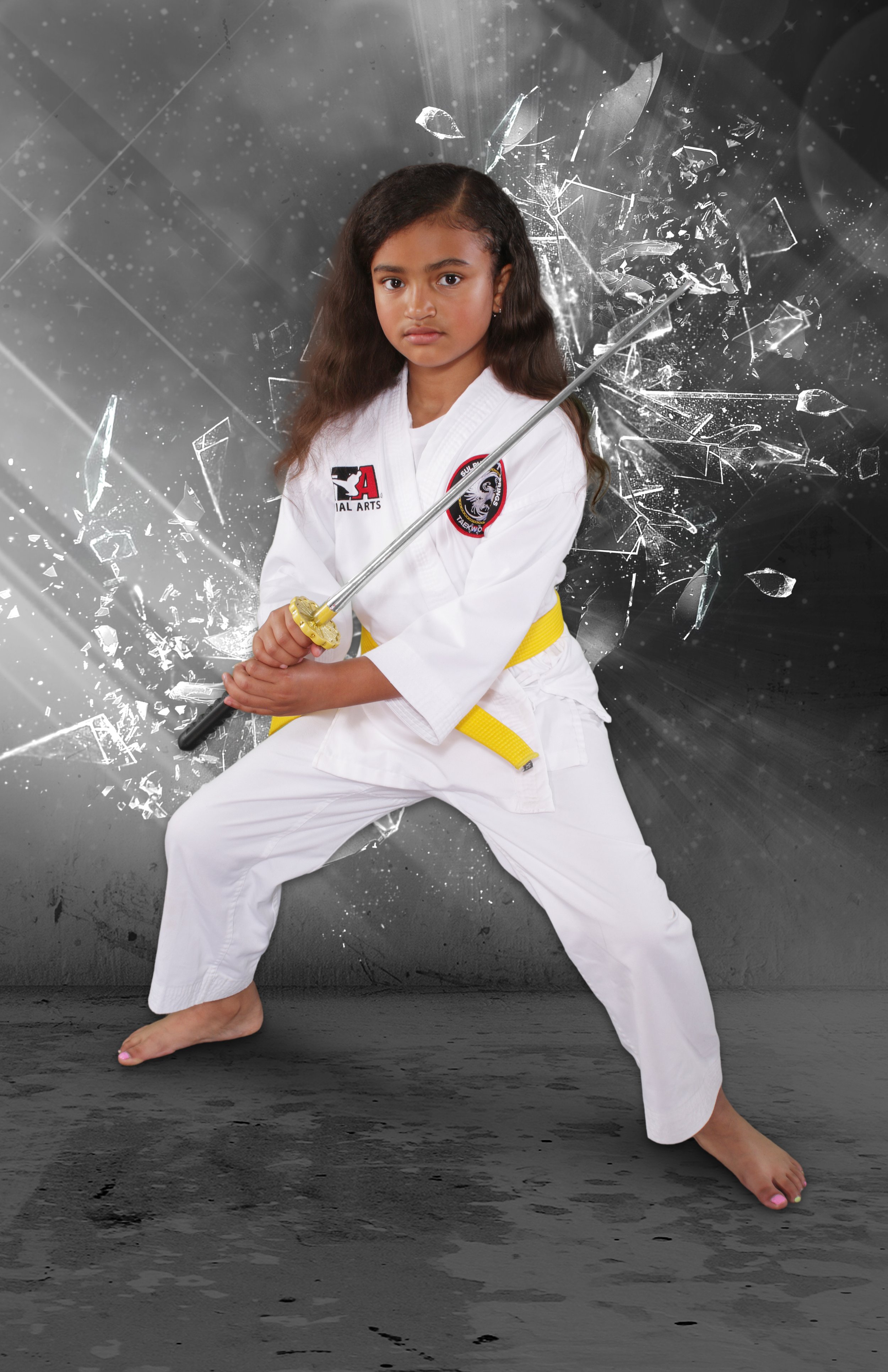 An image of a young girl in martial arts uniform holding a plastic sword