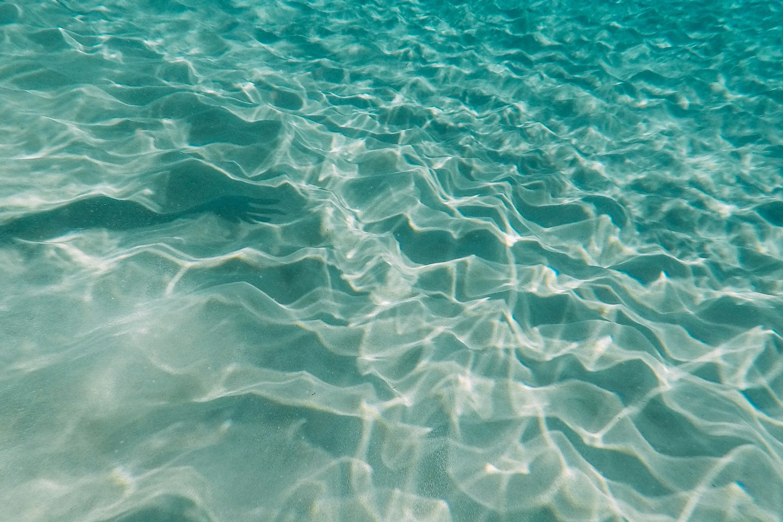 clear teal water with the sun shining on it