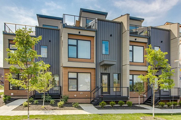 New construction of a three-story condo complex with large glass windows.