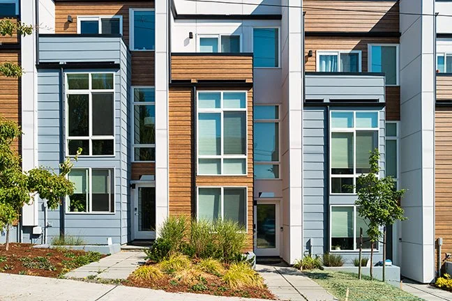 Three-story, multi-colored condo complex with large white framed windows, in the Pacific Northwest.