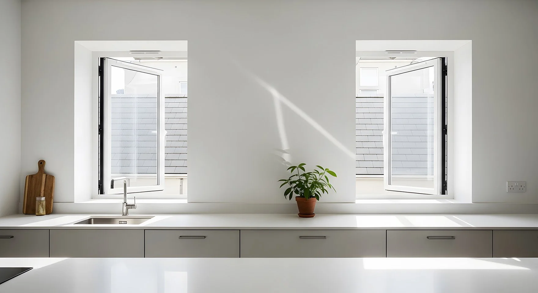 Two white-framed open casement windows above a modern, minimalistic kitchen counter.