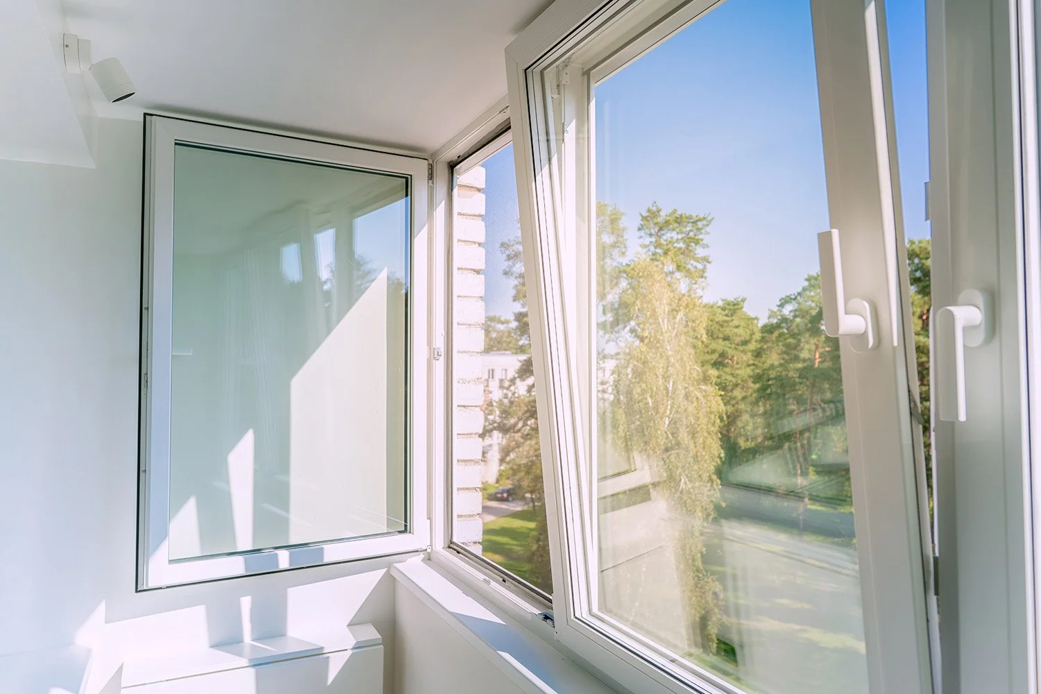 Two white framed tilt-turn windows next to each other. One is turned open and the other is tilted open.