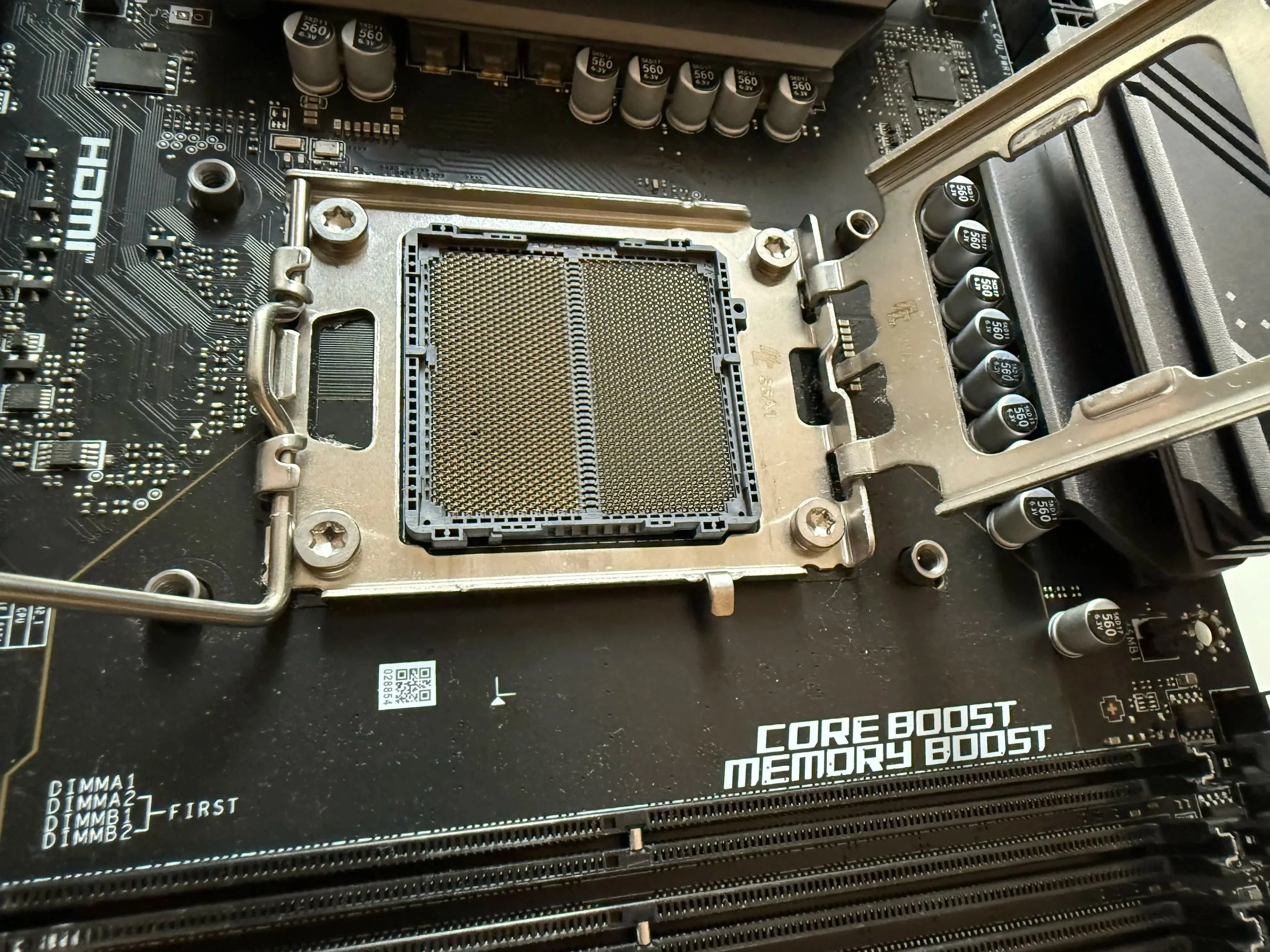 A close-up of a computer motherboard with a focus on the CPU socket, surrounding capacitors, and slots. The motherboard features various electronic components and text indicating features like "Core Boost" and "Memory Boost."