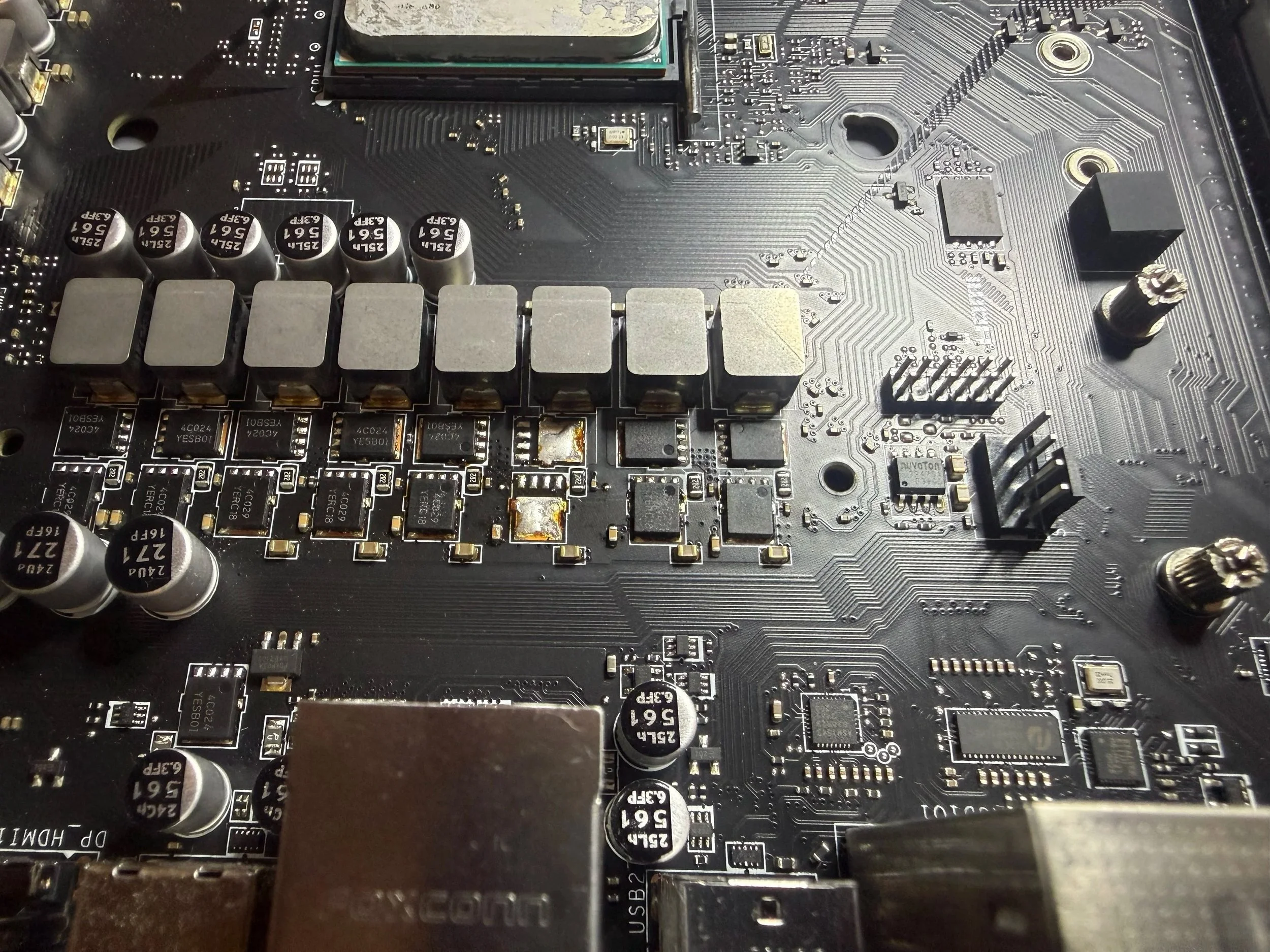 Innenansicht eines Computer-Motherboards mit verschiedenen elektronischen Komponenten, Kondensatoren, Chips und Steckverbindungen.