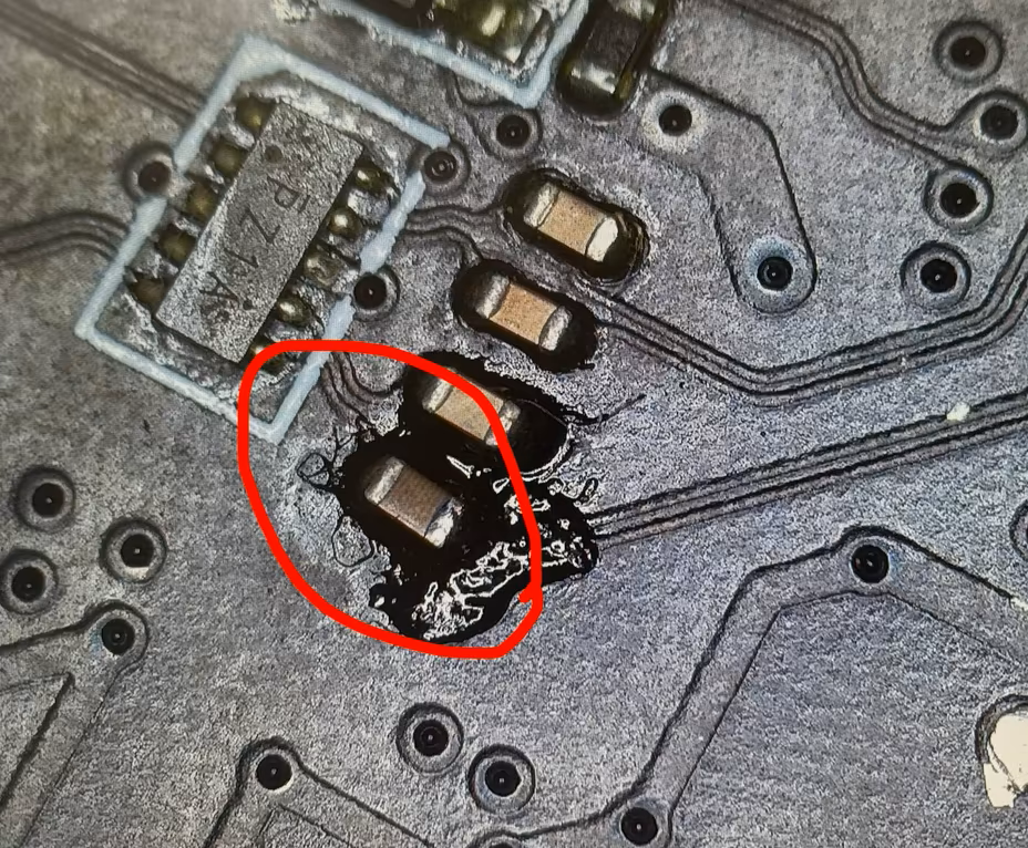 Ein Blick auf eine zerstörte elektronische Leiterplatte mit einem offenen Kabelbrand, hervorgehoben durch einen roten Kreis.