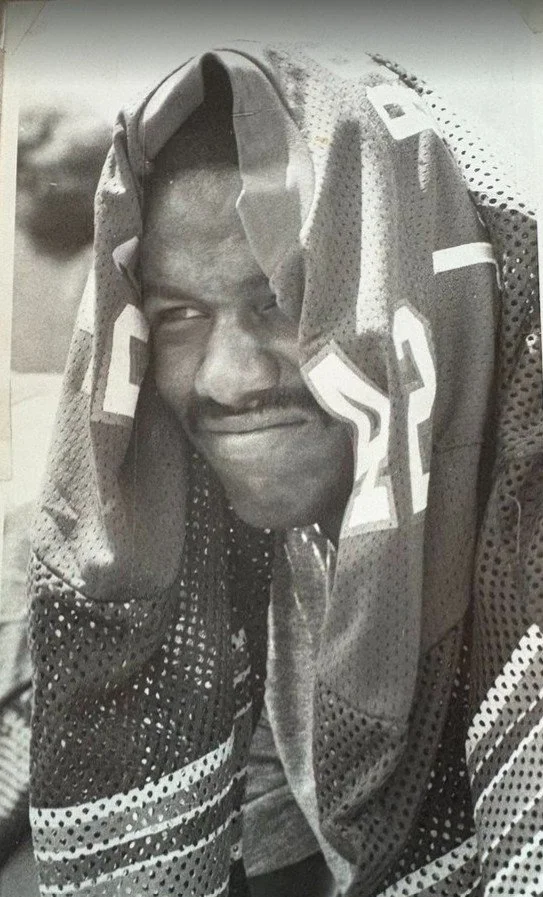 Man sitting watching a football game with a jersey over his head