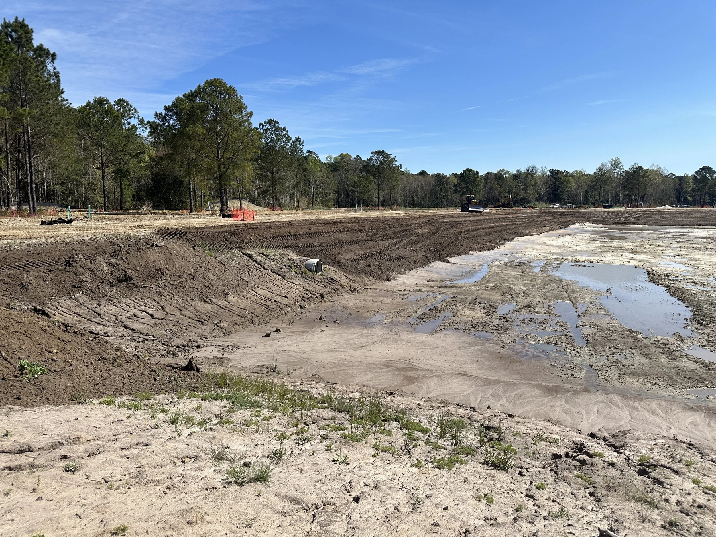 pond banks being dressed with top soil so that they can be stabilized with grass. pond construction