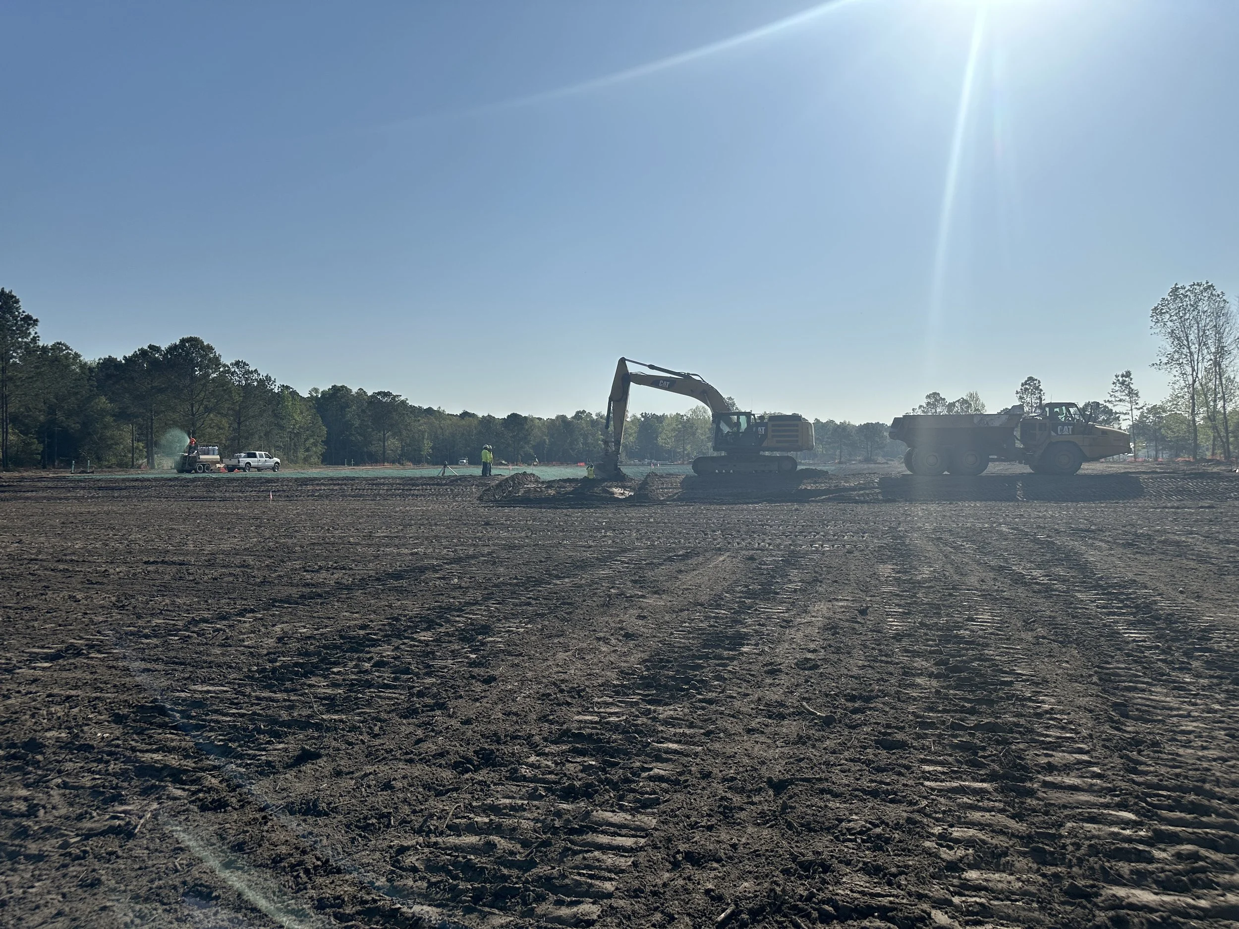 Excavator digging out for installation of weir wall between wet detention pond and dry pond
