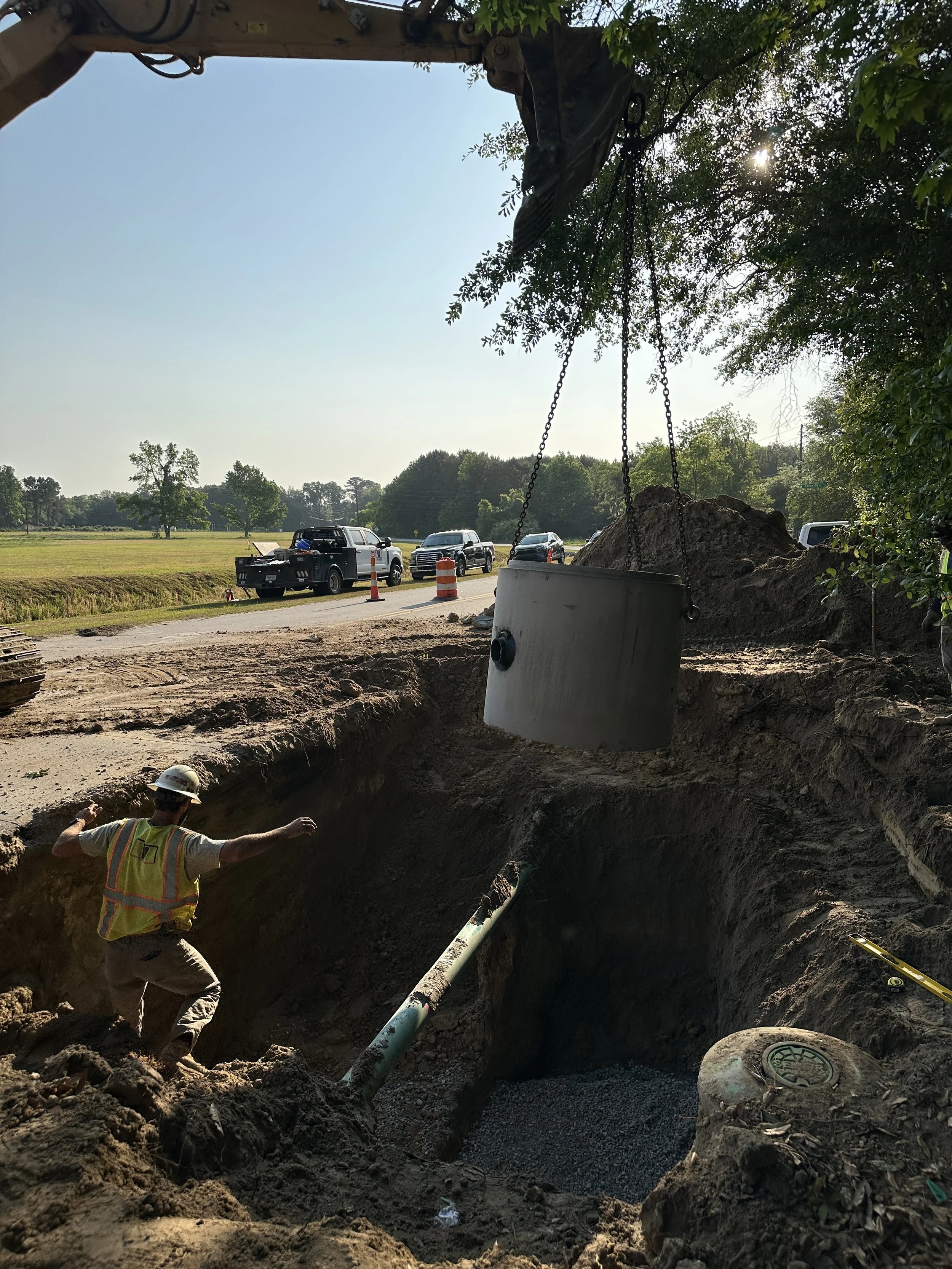 Lowering manhole into hole for forcemain connection
