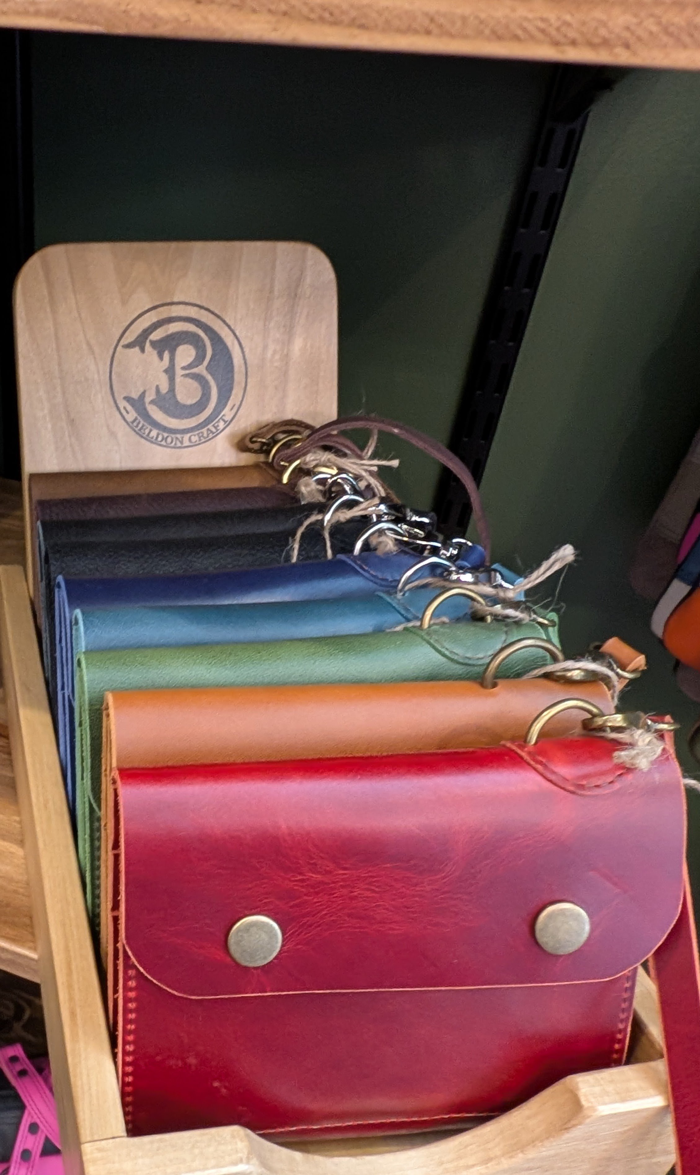 A display of colorful leather-bound notebooks with spiral bindings in a wooden tray.
