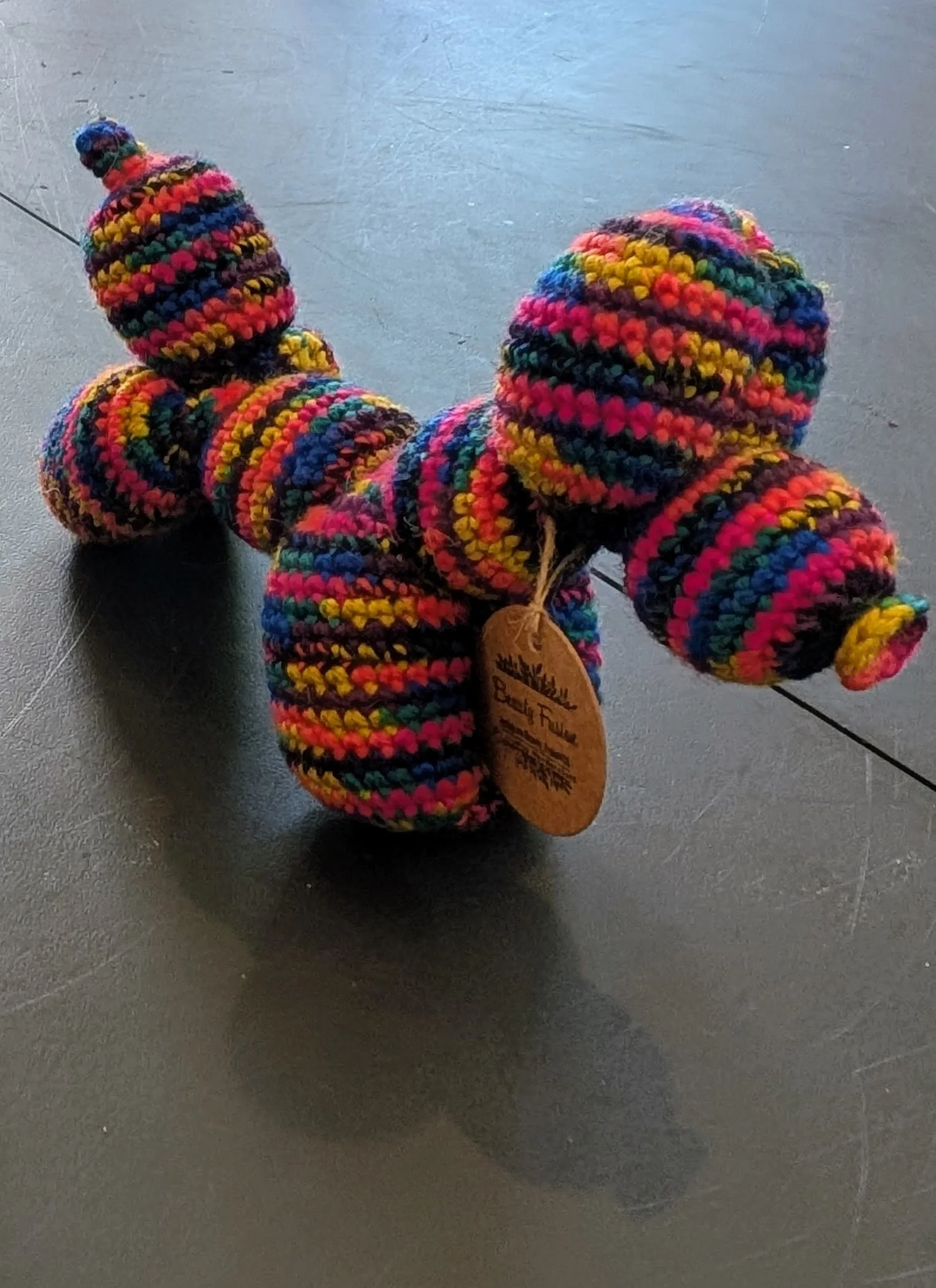 Pair of colorful, thickly knit woolen mittens on a dark surface.