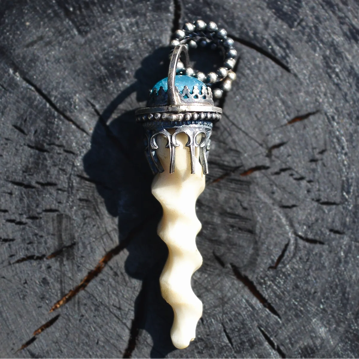 Handcrafted pet bone memorial necklace displayed on a black wooden background