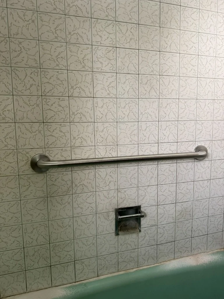 Horizontal grab bar installed in tiled shower, safety hardware installation