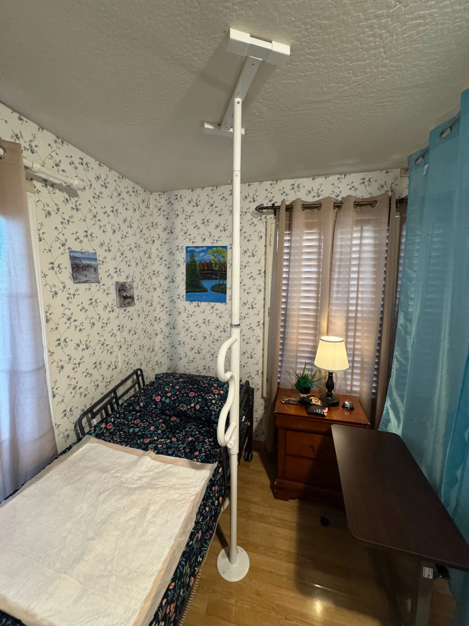 Floor to ceiling support pole installed beside bed, bedroom mobility aid setup
