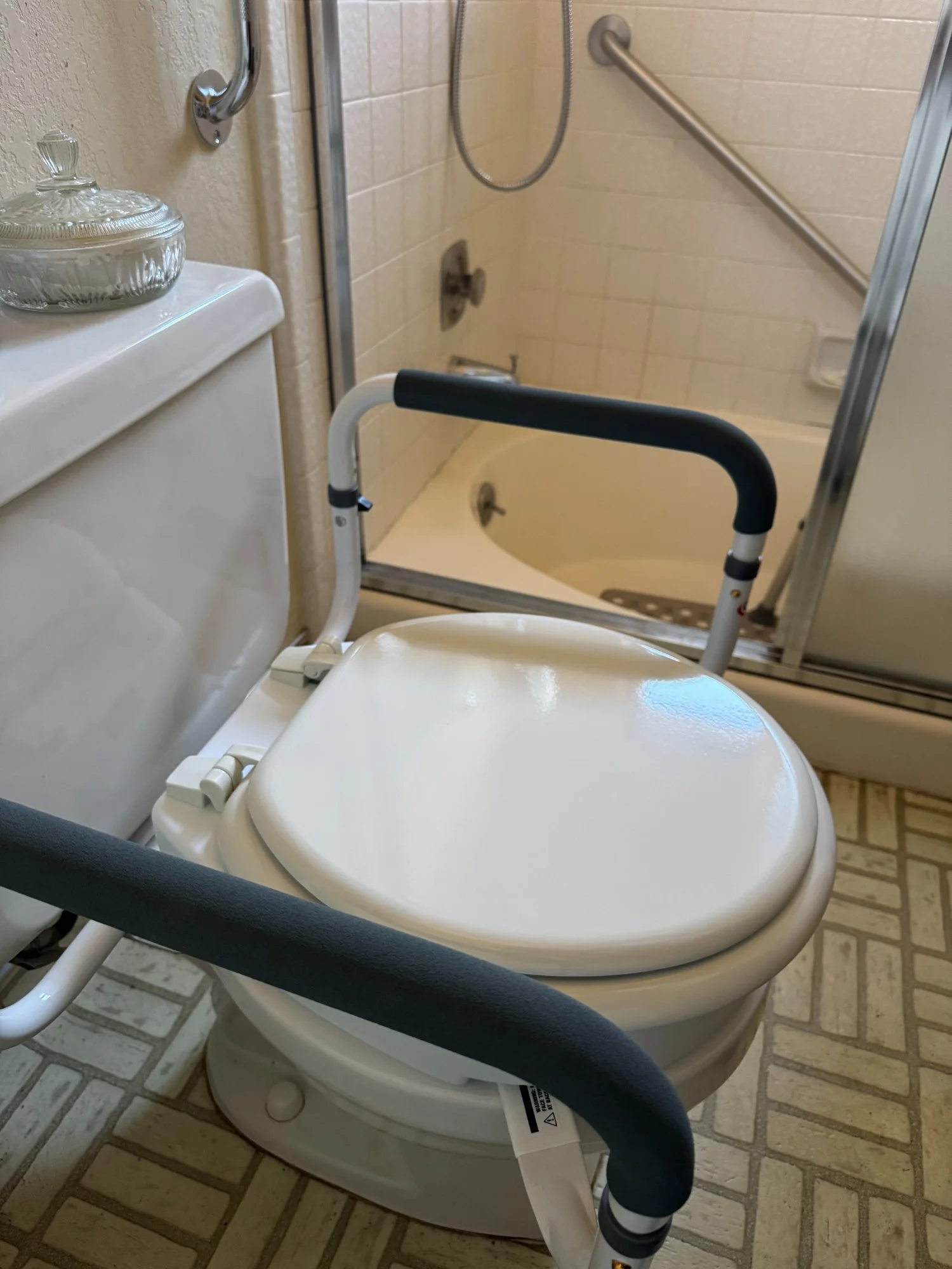 Toilet safety frame with support rails installed beside bathtub, home mobility modification.